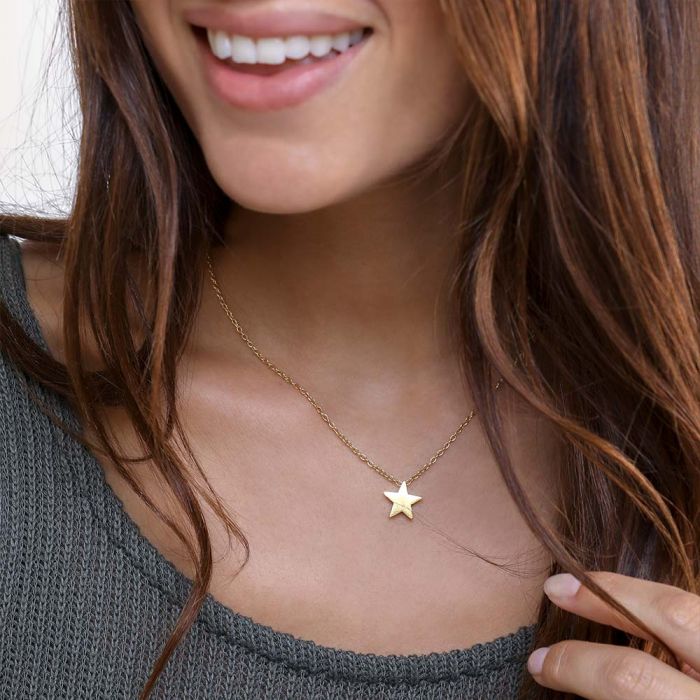 Colier delicat din alamă cu pandantiv stea, purtat la baza gâtului pentru un look minimalist și feminin.