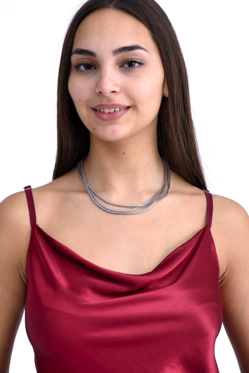 Model purtând un colier multifir argintiu, asortat cu un top satinat de culoare bordo, cu bretele subțiri.