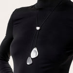 Colier cu șnur negru și două pandantive în formă de petale metalice, realizate din aluminiu 100% reciclat, prezentat pe fundal alb.