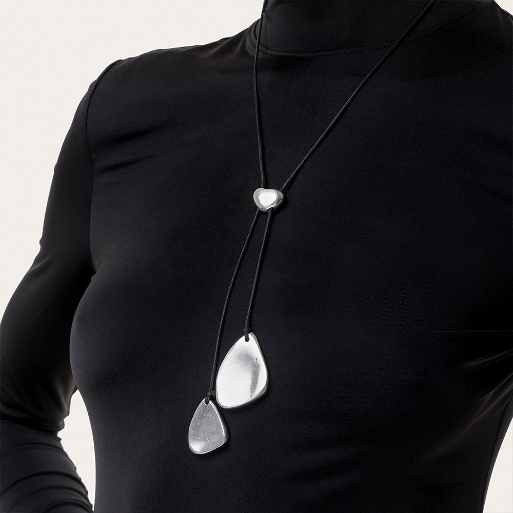 Colier cu șnur negru și două pandantive în formă de petale metalice, realizate din aluminiu 100% reciclat, prezentat pe fundal alb.