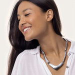 Colier reglabil cu 8 bare din aluminiu reciclat, lucrat manual, purtat de o femeie pe gât, stil modern și elegant.