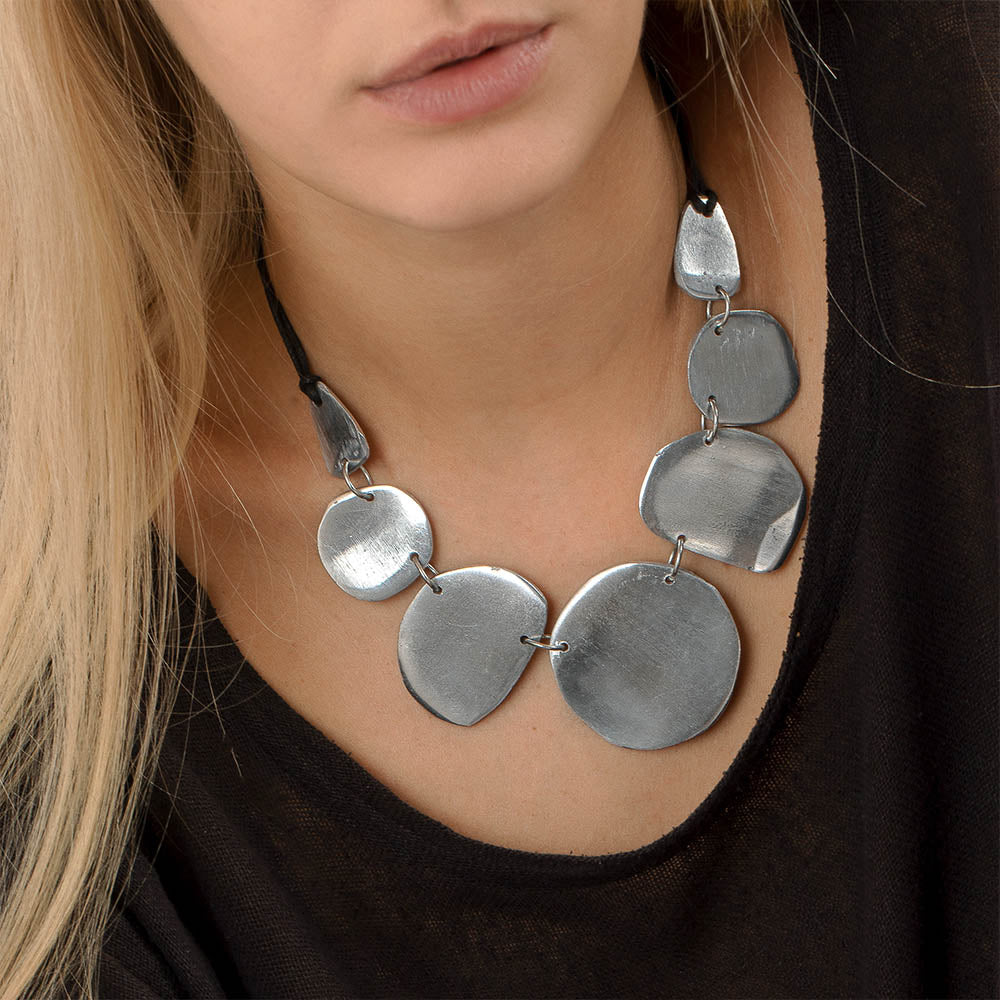 Colier scurt semirotund cu plăci fine din aluminiu reciclat, lucrat manual, purtat la baza gâtului pe șnur textil negru.