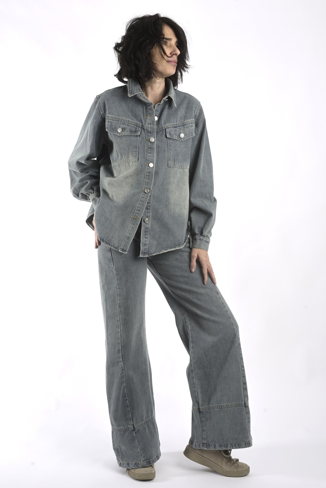 Vedere integrală a compleului din denim gri, cu bluză cu nasturi și pantaloni lungi, purtat lejer.