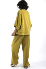 Vedere din spate a compleului lejer, bluză amplă și pantaloni cu croială largă, aspect relaxat.