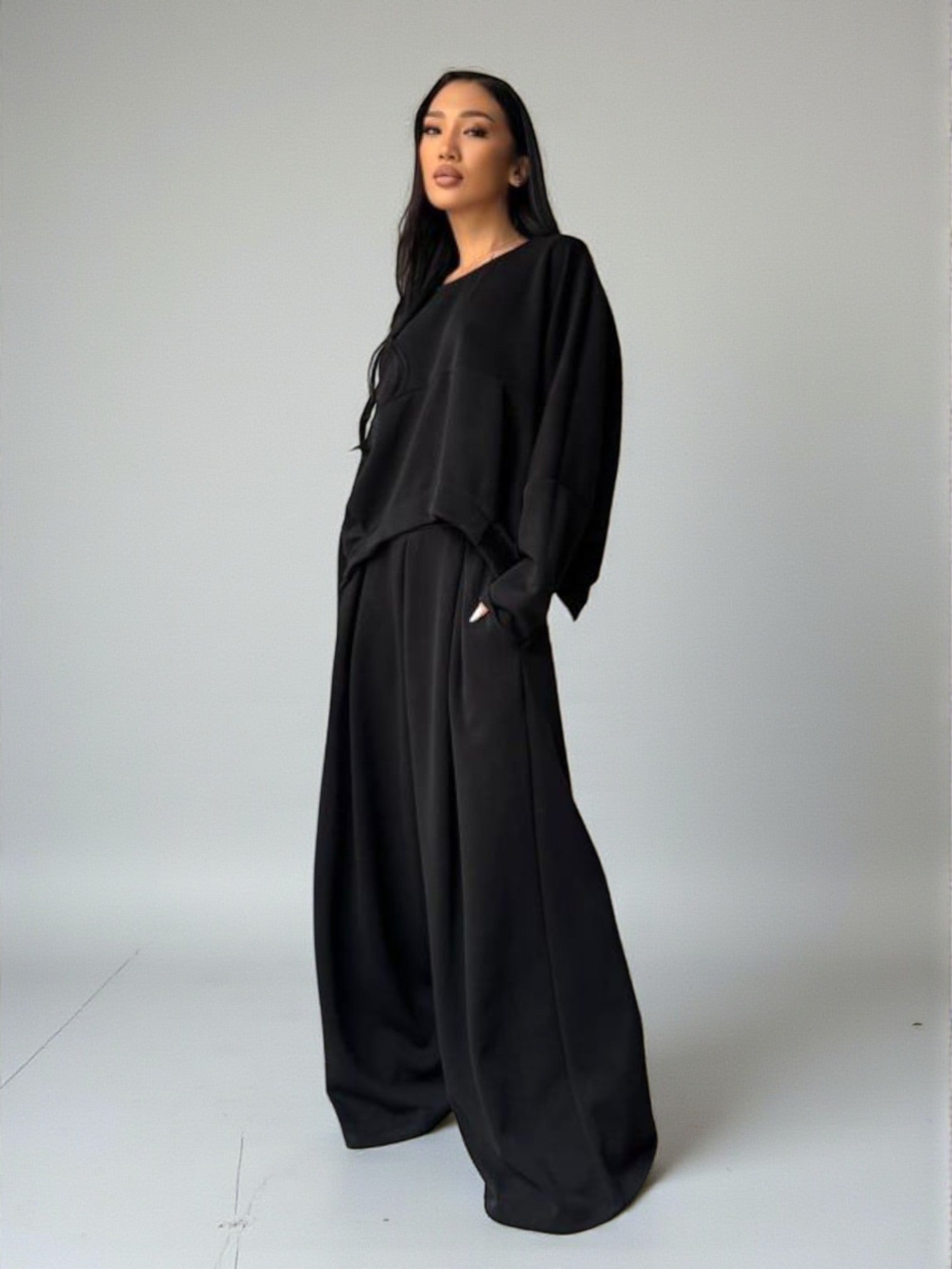 Compleu negru cu bluză raglan și pantaloni largi cu pliu, croială fluidă și lungime amplă.