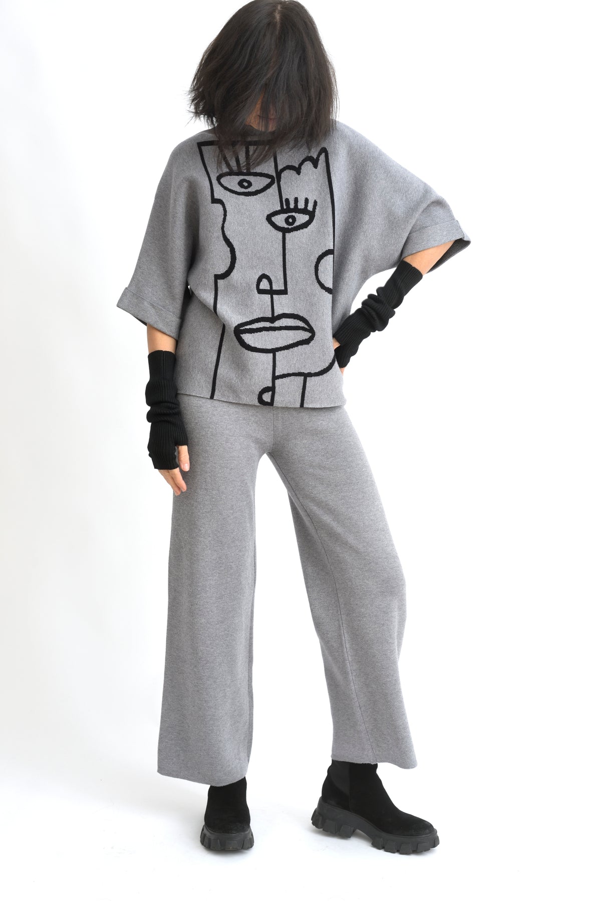 Vedere laterală a compleului cu top imprimat cu portret stilizat și pantaloni drepți, croială relaxată.