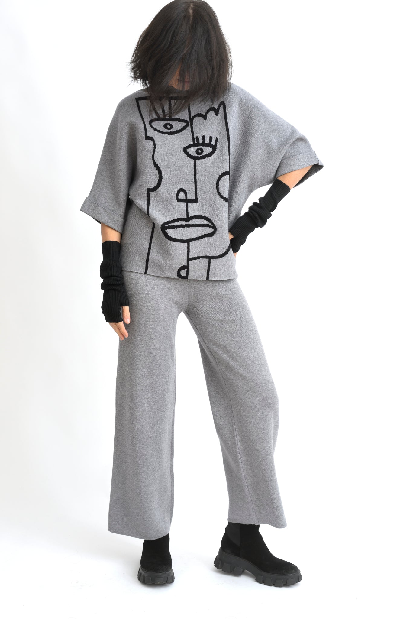 Vedere laterală a compleului cu top imprimat cu portret stilizat și pantaloni drepți, croială relaxată.