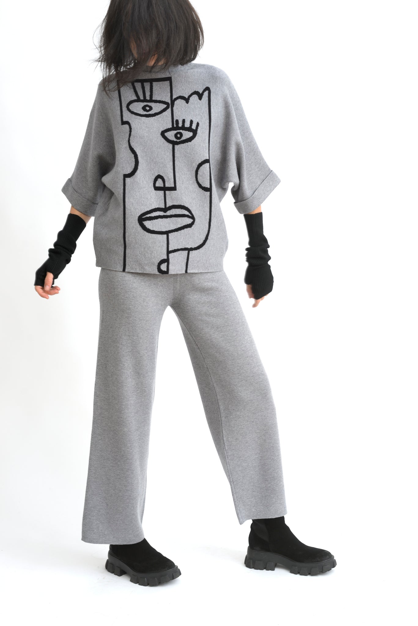Model purtând compleul bej, top oversize cu portret abstract și pantaloni cu croială comodă.
