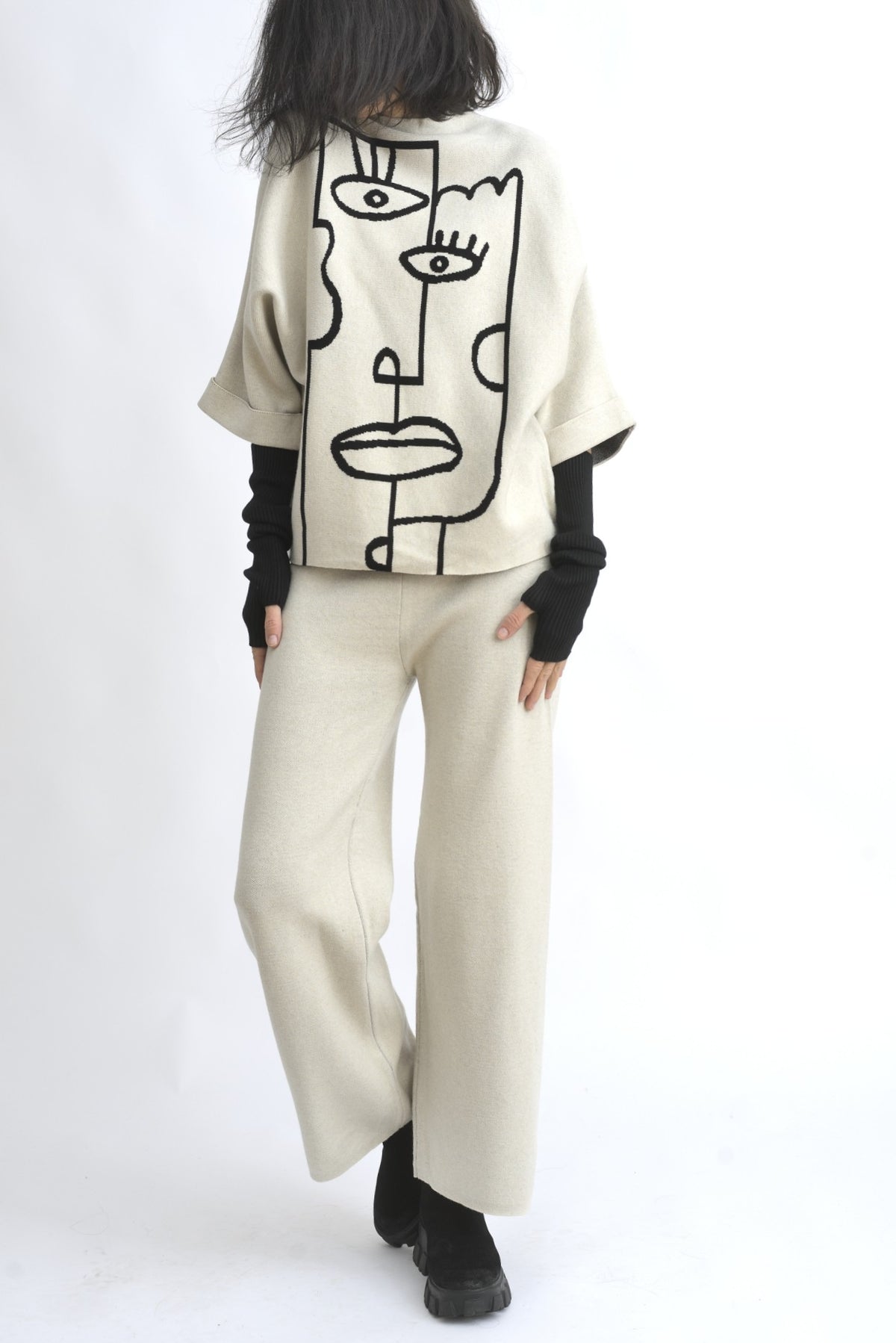 Vedere din spate a compleului bej, cu top lejer și pantaloni largi din tricot, talie elastică.