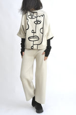 Vedere din spate a compleului bej, cu top lejer și pantaloni largi din tricot, talie elastică.