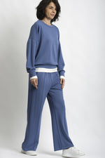 Compleu de trening albastru cu bluză lejeră și pantaloni drepți, cu terminație din tricot alb.