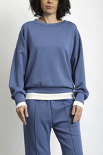 Detaliu de terminație din tricot alb la bluză și pantaloni, contrast subtil și curat.