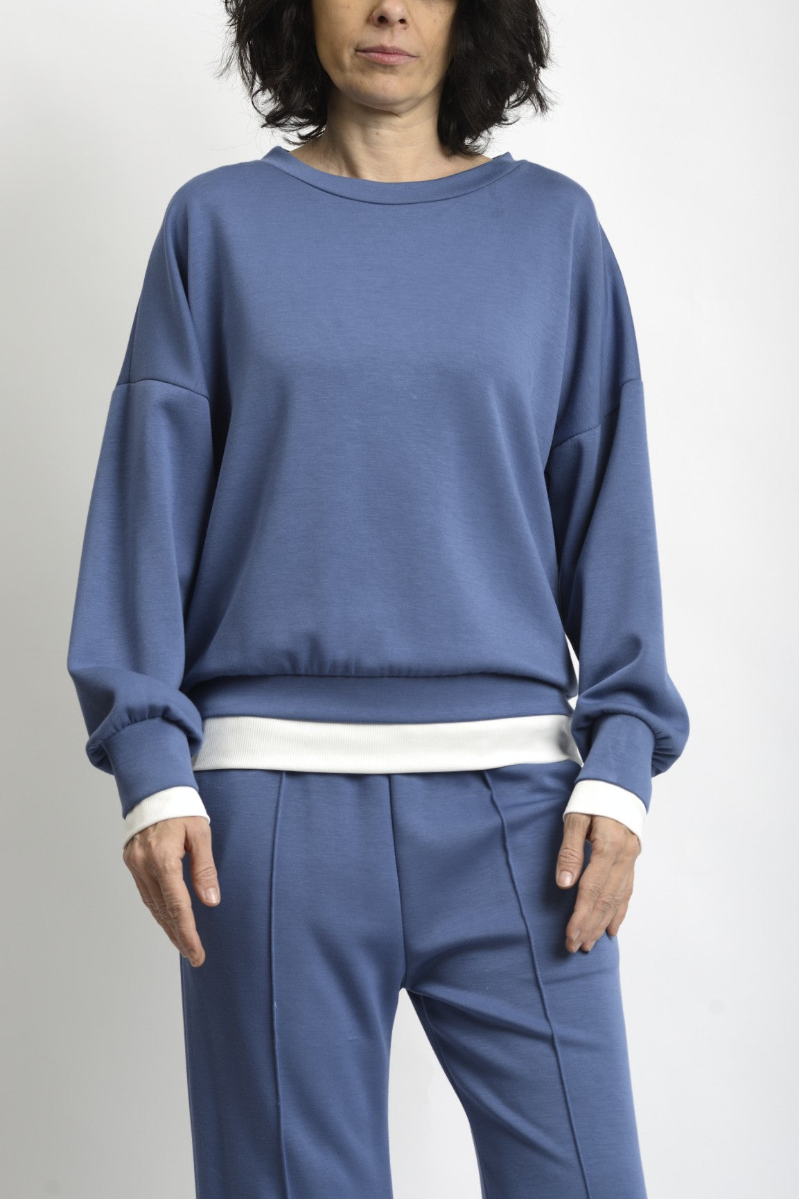 Detaliu de terminație din tricot alb la bluză și pantaloni, contrast subtil și curat.