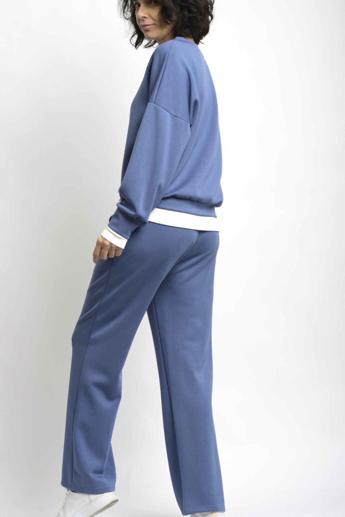 Spatele compleului de trening, cu bluză lejeră și pantaloni cu talie elastică.