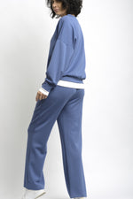 Spatele compleului de trening, cu bluză lejeră și pantaloni cu talie elastică.