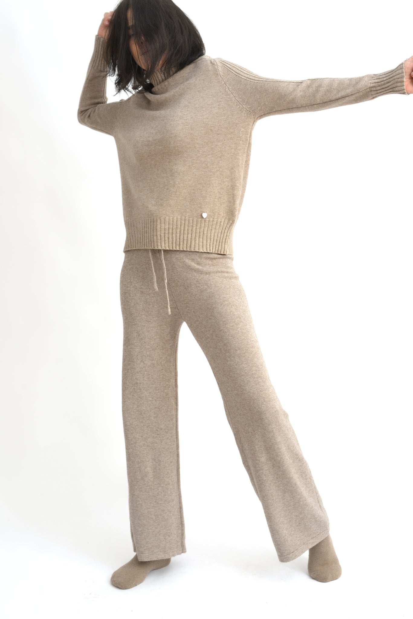 Compleu crem din tricot cu top lejer și pantaloni evazați, realizat din material moale și elastic.