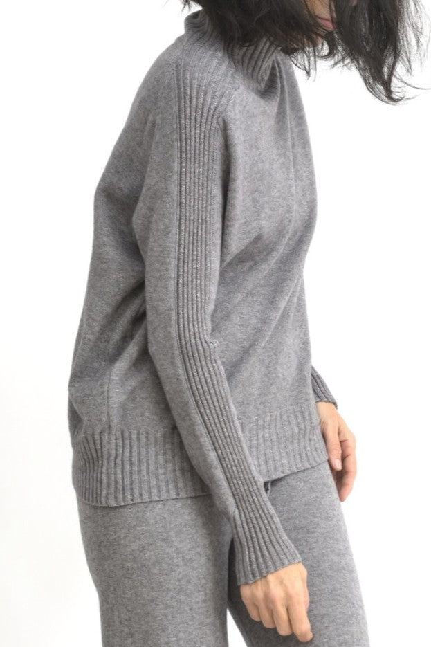 Vedere laterală a unui compleu gri din tricot, cu top ribbed și pantaloni largi elastici.