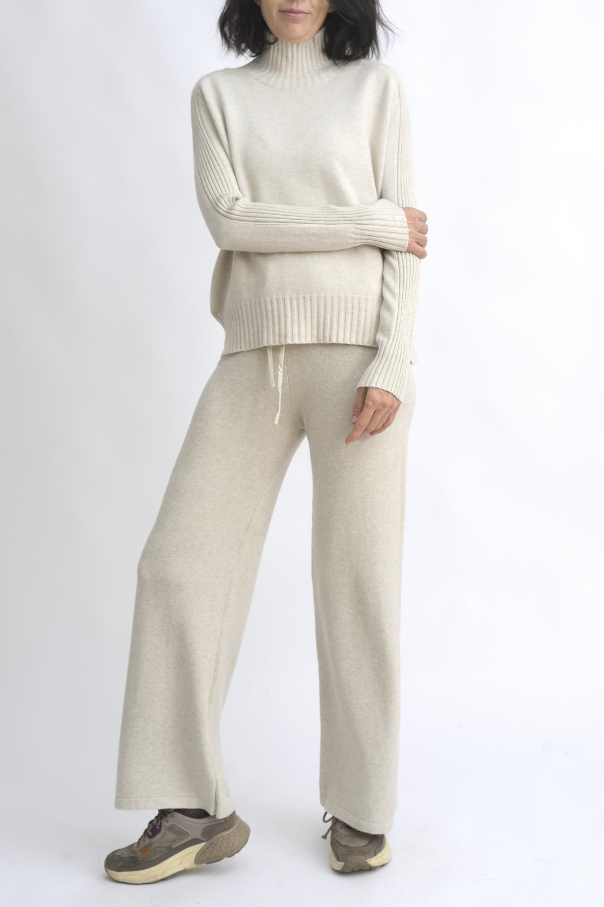 Compleu din tricot bej format din top cu dungi rib și umeri căzuți, asortat cu pantaloni largi din același material.