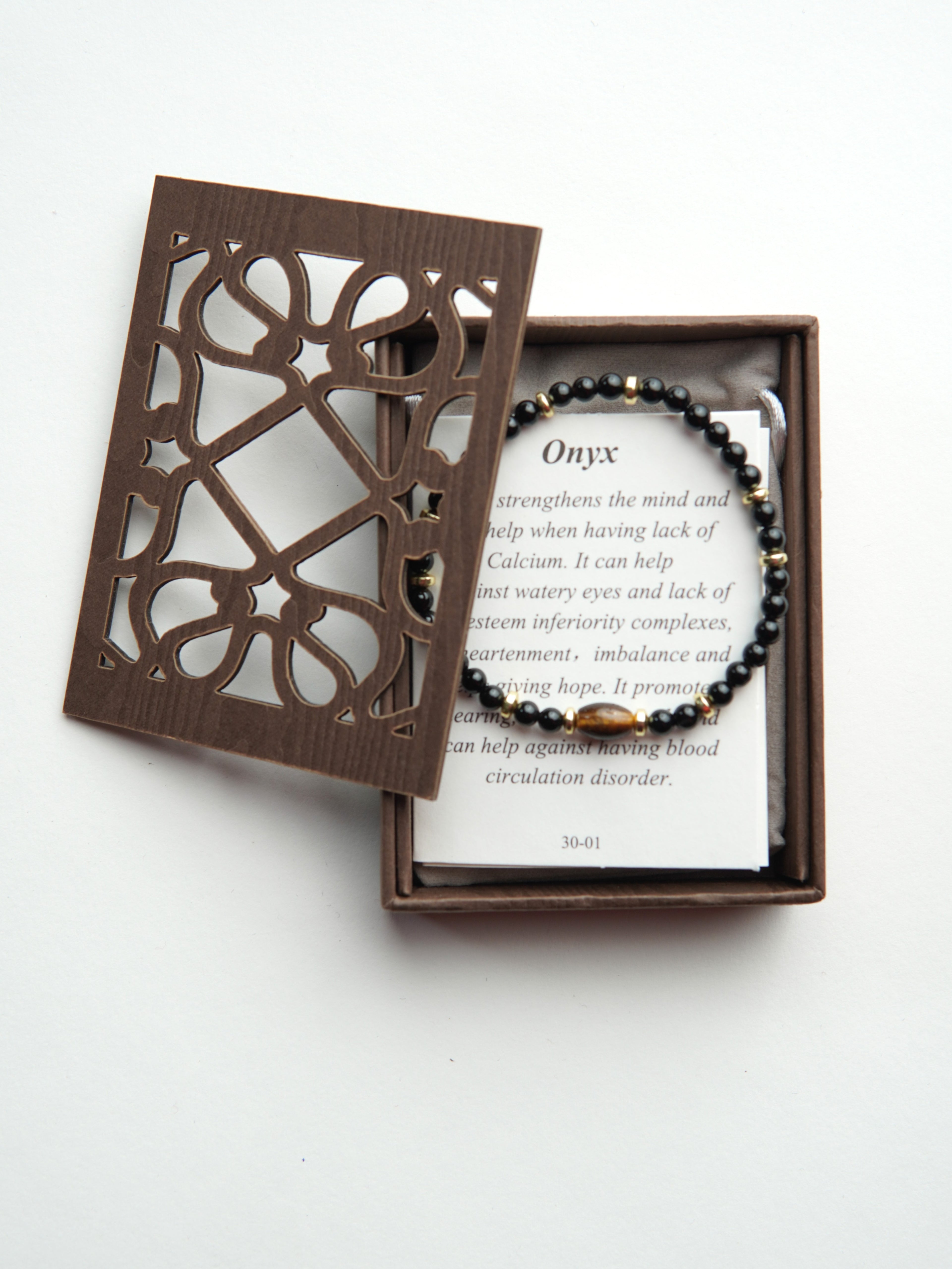 Cutie din lemn cu model geometric decupat, potrivită pentru depozitarea unei brățări.