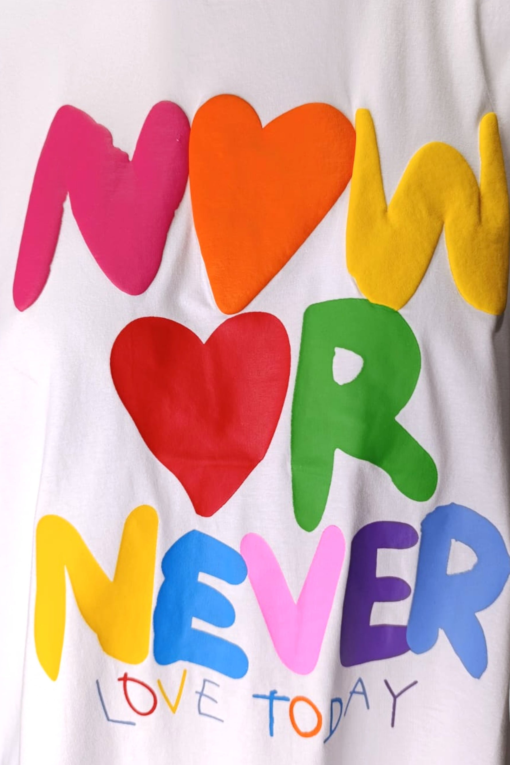 Detaliu imprimeu „Now or Never” pe tricou alb cu litere și inimi colorate — All Above Boutique.