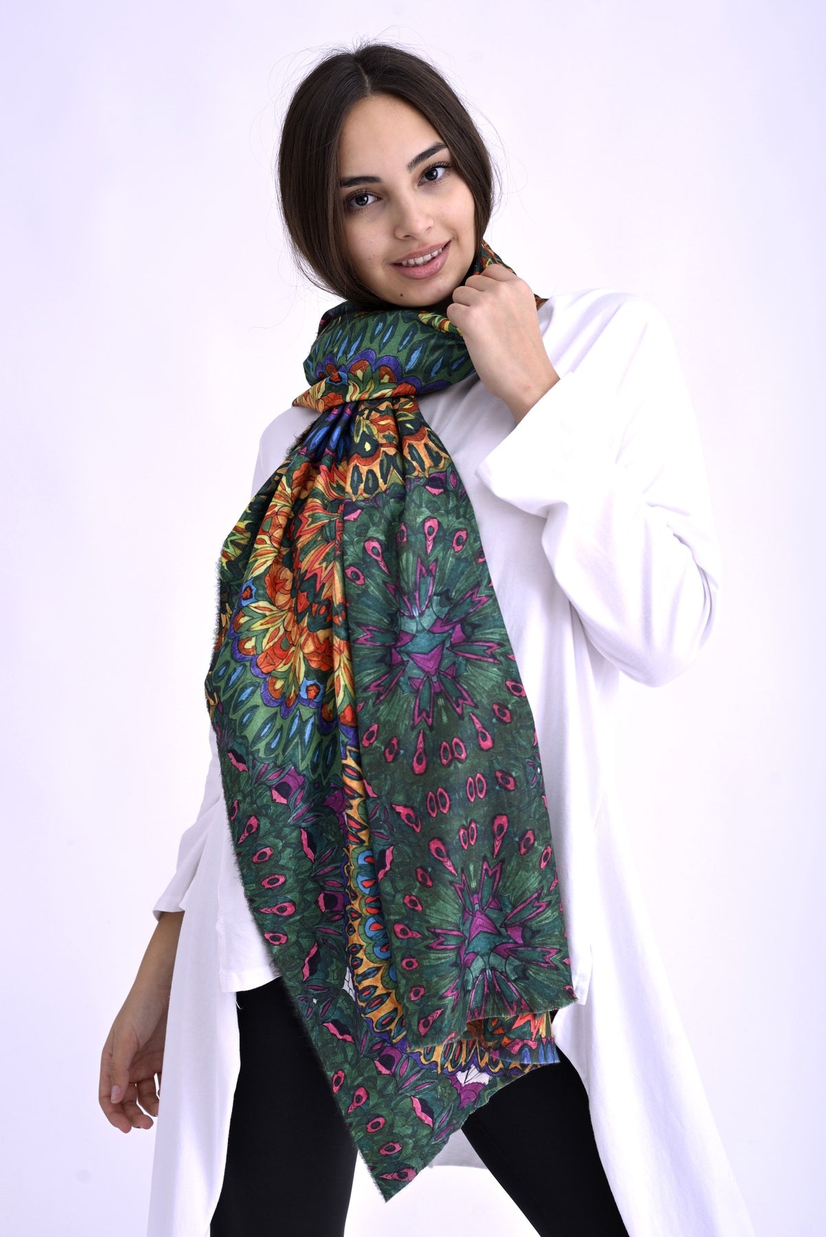 Model purtând o eșarfă amplă multicoloră, cu imprimeu floral vibrant pe fundal verde, asortată la o bluză albă lungă.