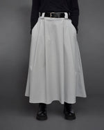 Fustă midi gri, combinată cu top negru și ghete masive, stil casual elegant.