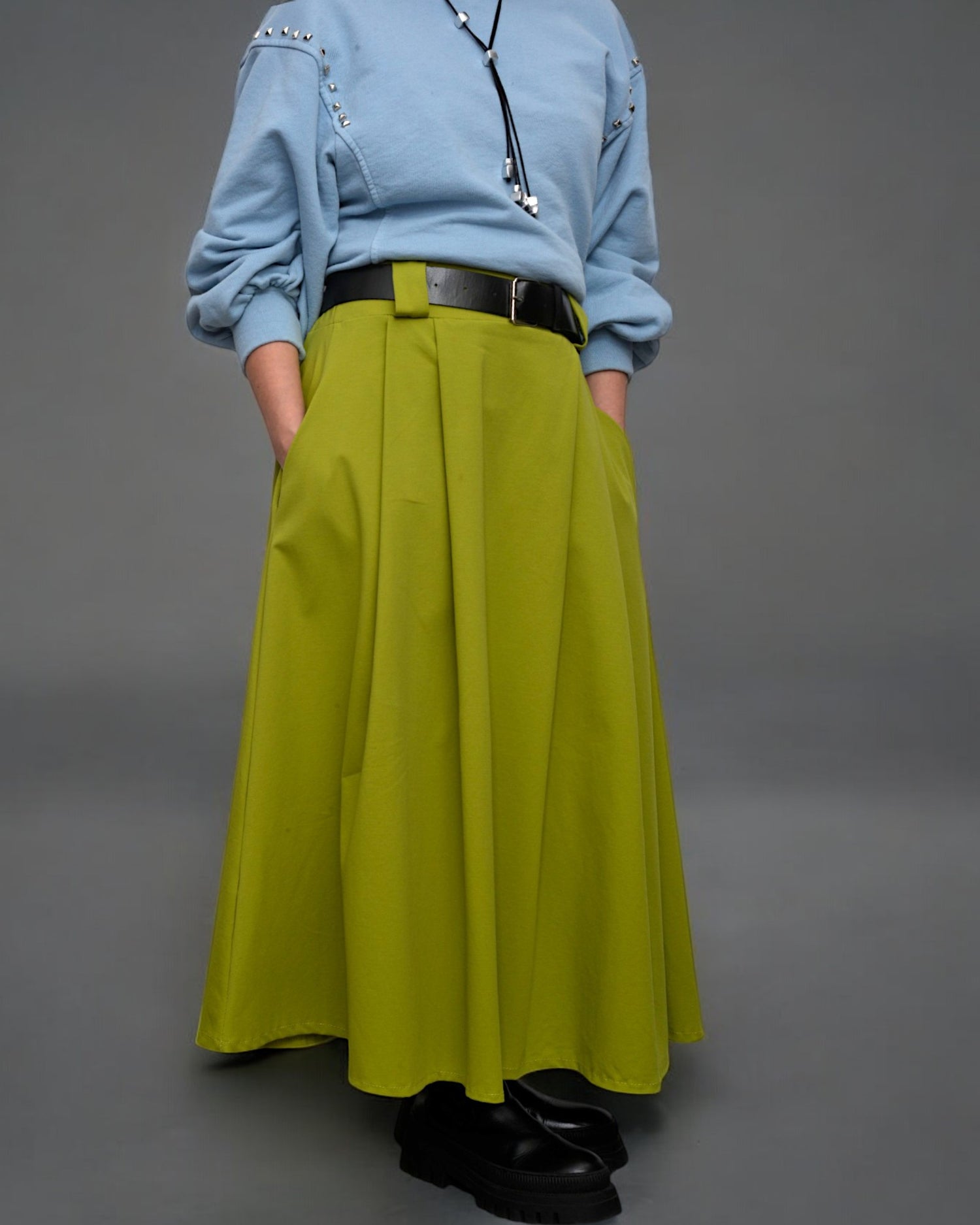 Fustă midi verde închis, accesorizată cu o bluză lejeră și ghete masive.