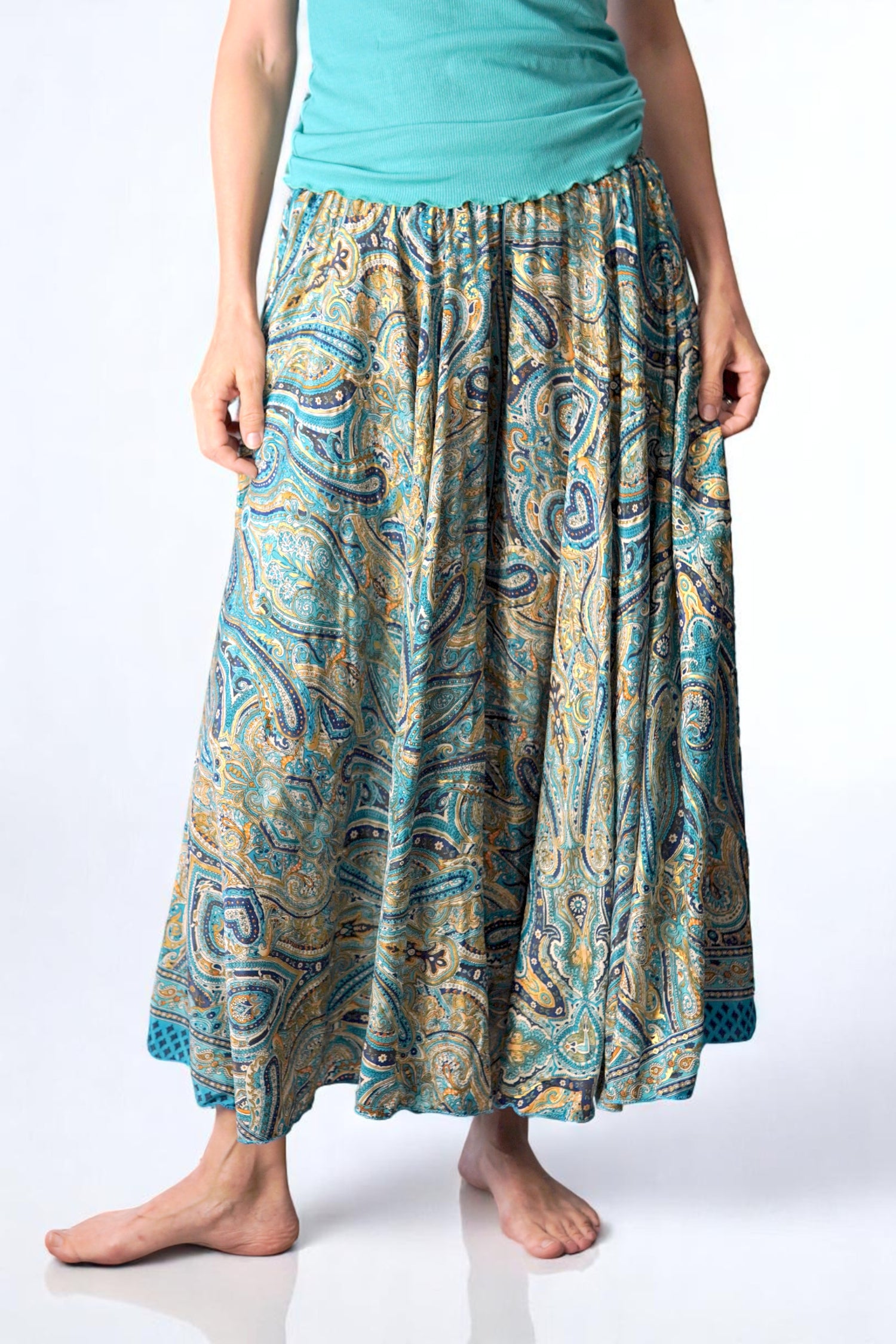 Fustă-pantalon tip șalvar cu imprimeu paisley în nuanțe de turcoaz, auriu și bleumarin, purtată cu un top verde mentă. Design amplu și lejer, ideal pentru vară și stiluri boho.