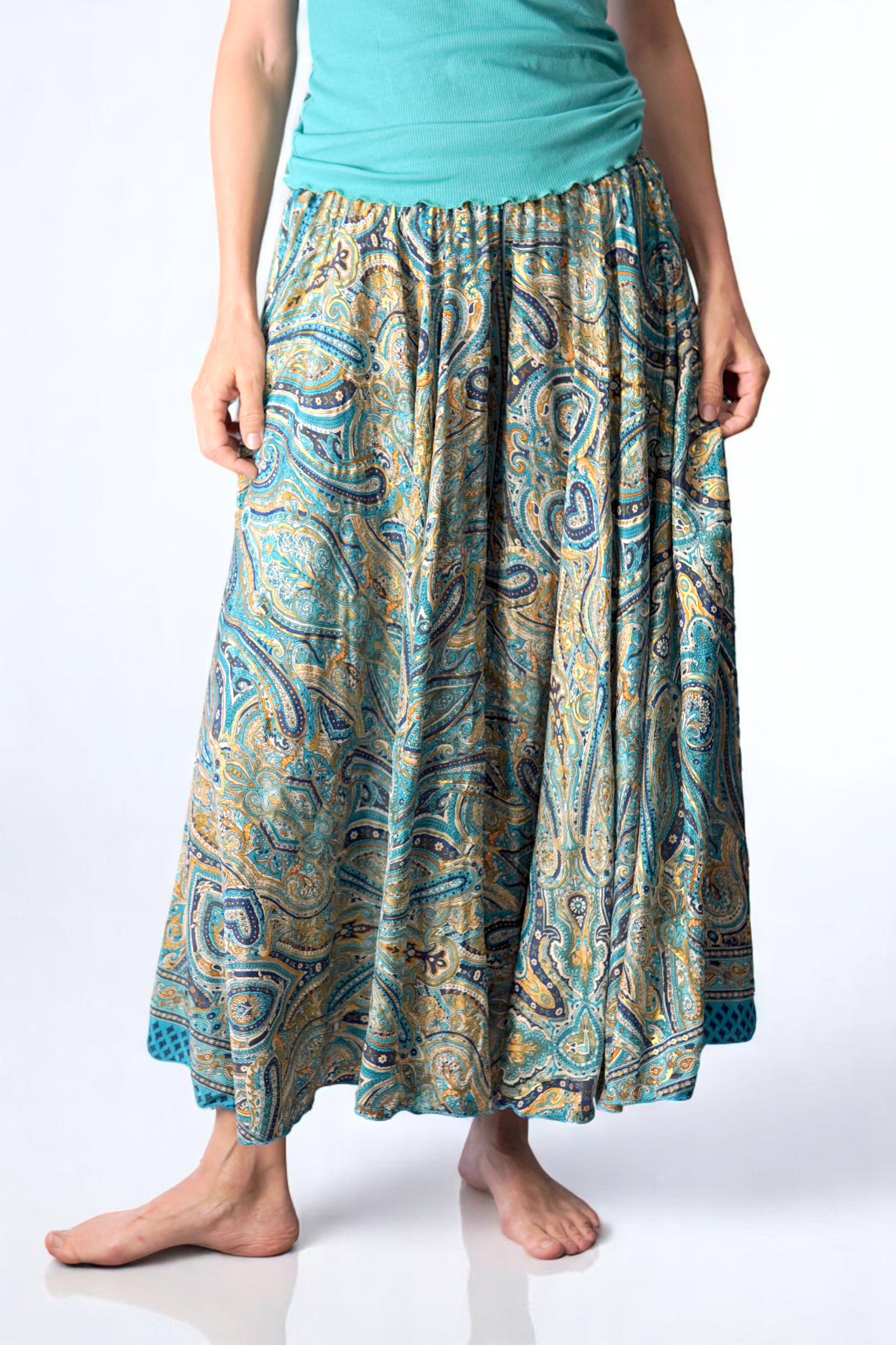 Fustă-pantalon tip șalvar cu imprimeu paisley în nuanțe de turcoaz, auriu și bleumarin, purtată cu un top verde mentă. Design amplu și lejer, ideal pentru vară și stiluri boho.