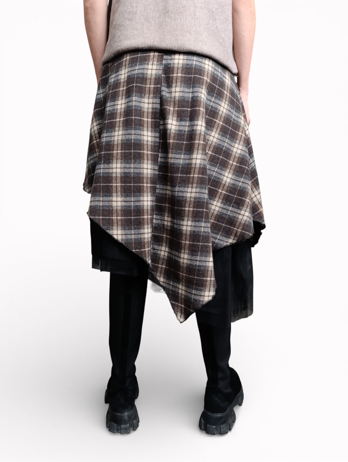 Fustă în carouri văzută din spate, cu croială asimetrică și strat de tul negru, purtată cu bocanci.