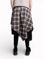 Fustă în carouri văzută din spate, cu croială asimetrică și strat de tul negru, purtată cu bocanci.