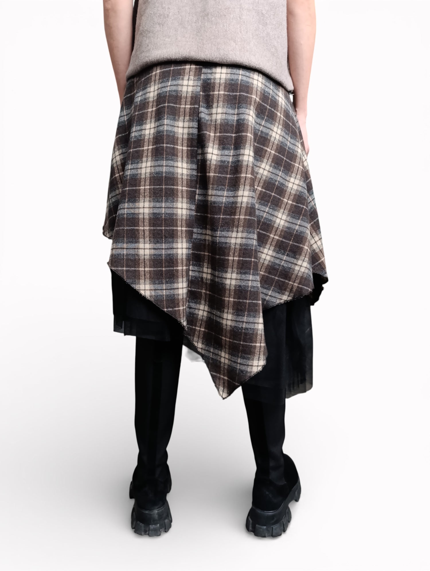 Fustă în carouri văzută din spate, cu croială asimetrică și strat de tul negru, purtată cu bocanci.