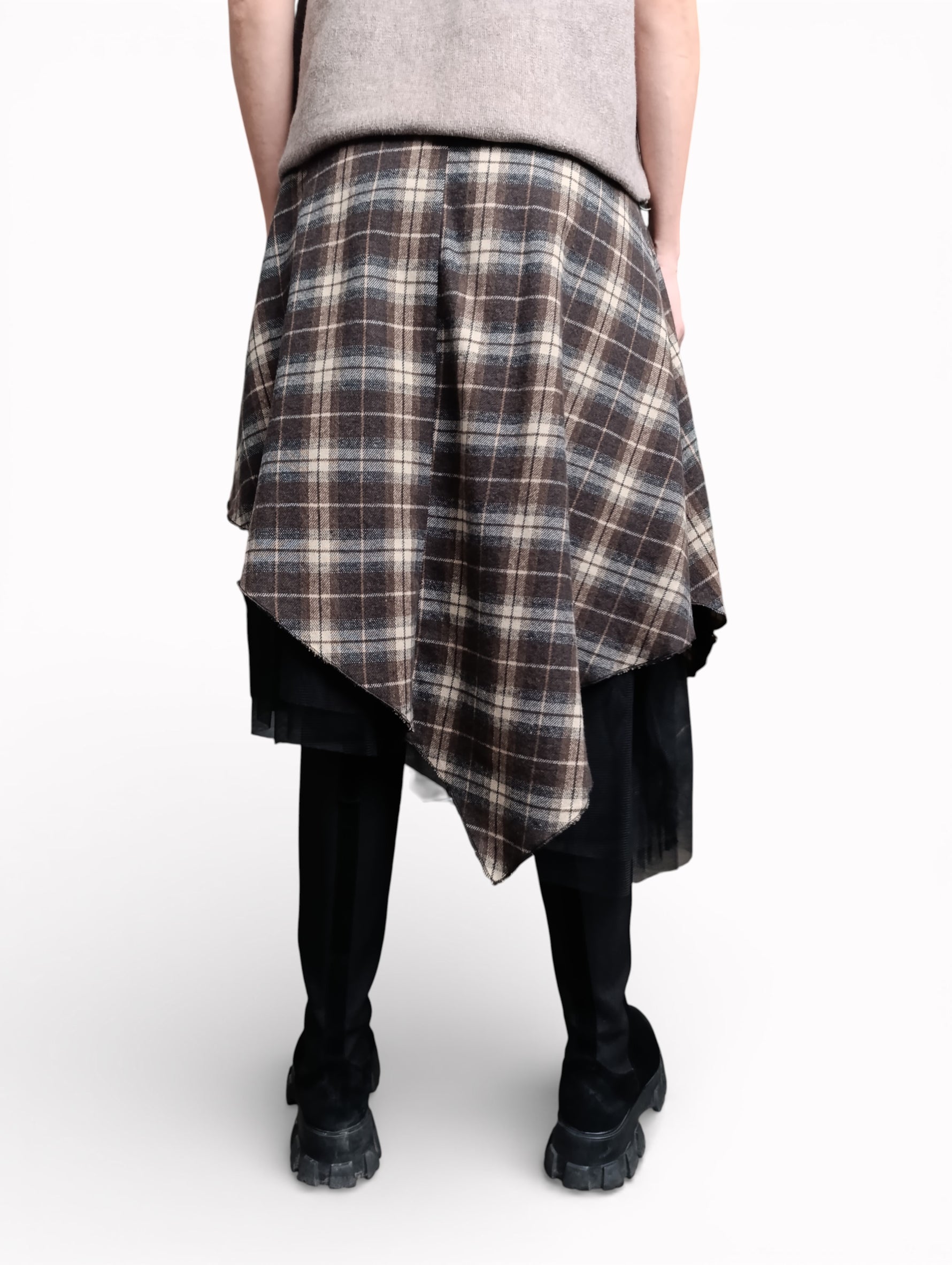 Fustă în carouri văzută din spate, cu croială asimetrică și strat de tul negru, purtată cu bocanci.