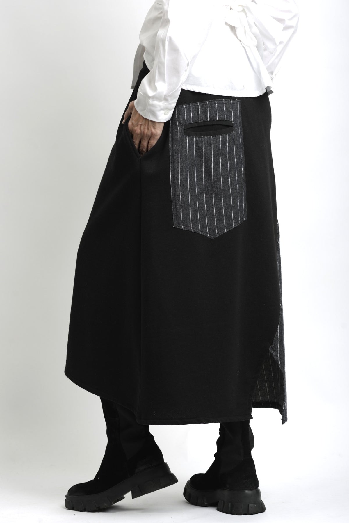 Vedere laterală a fustei asimetrice din jerse, cu contrast textural între materialul mat și cel tip jeans.