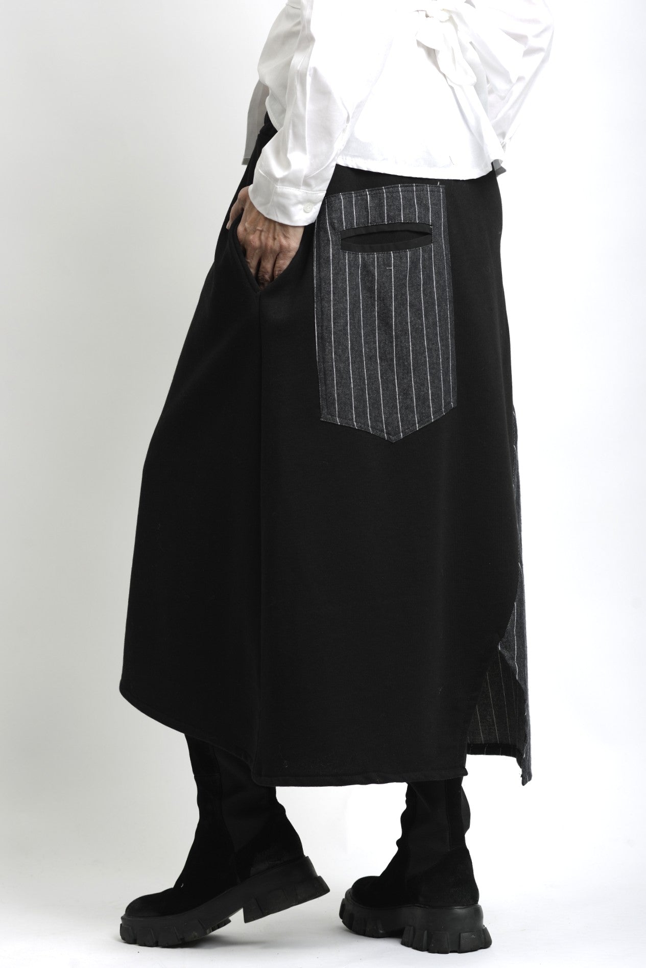 Vedere laterală a fustei asimetrice din jerse, cu contrast textural între materialul mat și cel tip jeans.