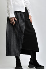 Vedere laterală a fustei asimetrice din jerse, cu contrast textural între materialul mat și cel tip jeans.