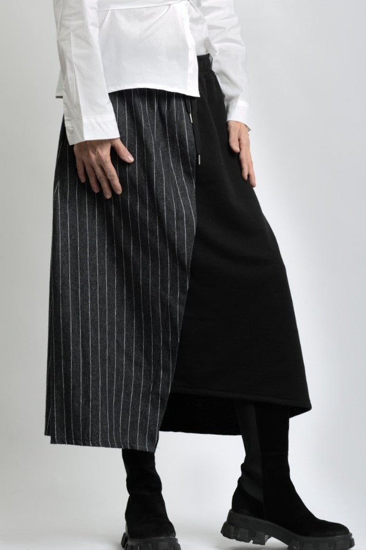 Vedere laterală a fustei asimetrice din jerse, cu contrast textural între materialul mat și cel tip jeans.