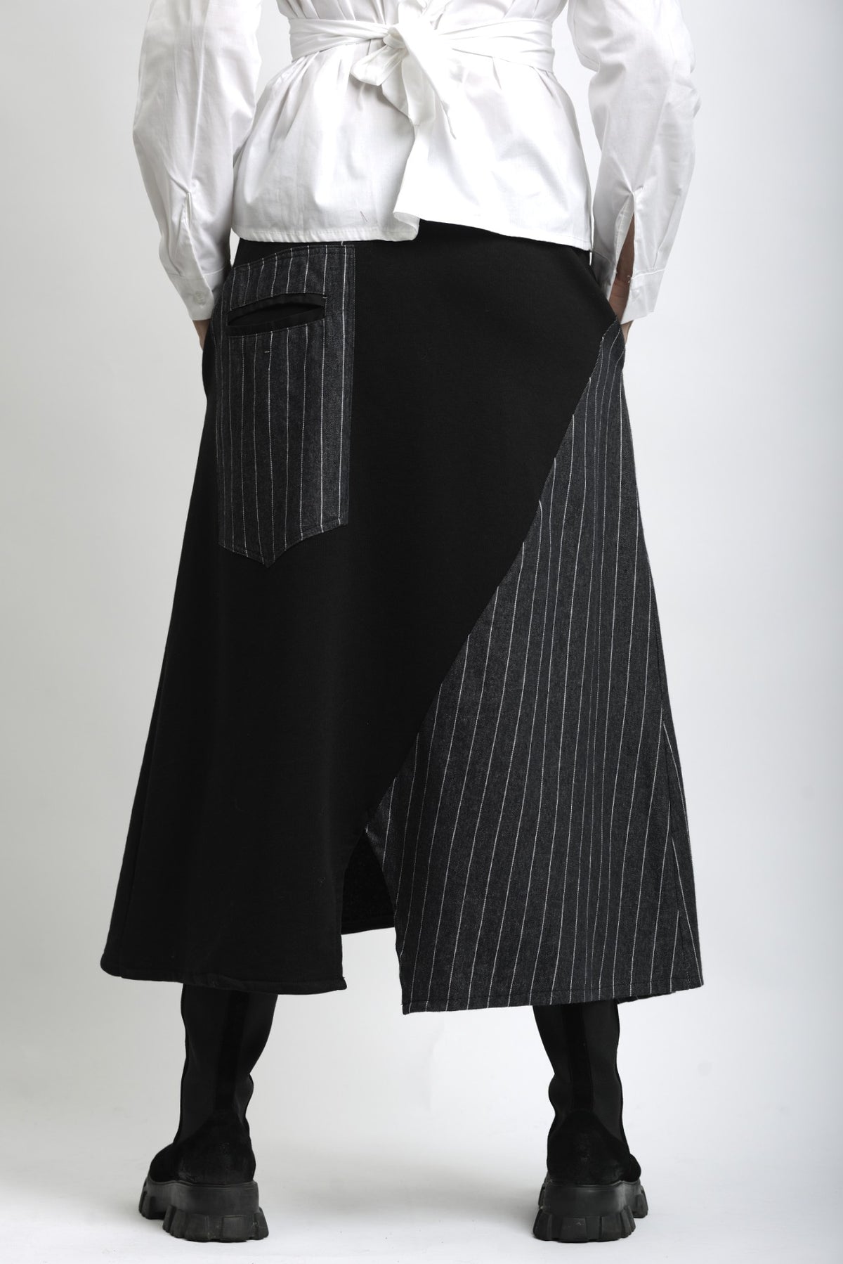 Spatele fustei asimetrice din jerse, cu lungime midi și cădere fluidă.