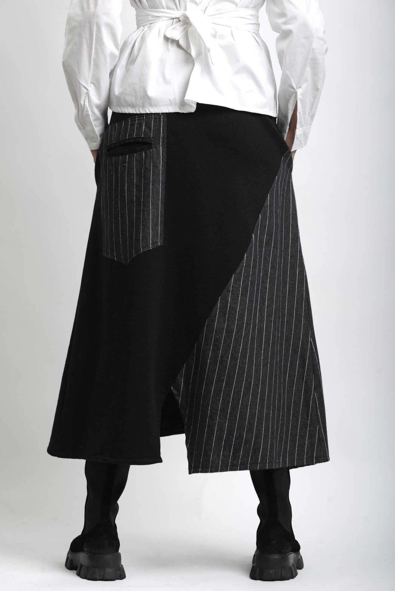 Spatele fustei asimetrice din jerse, cu lungime midi și cădere fluidă.