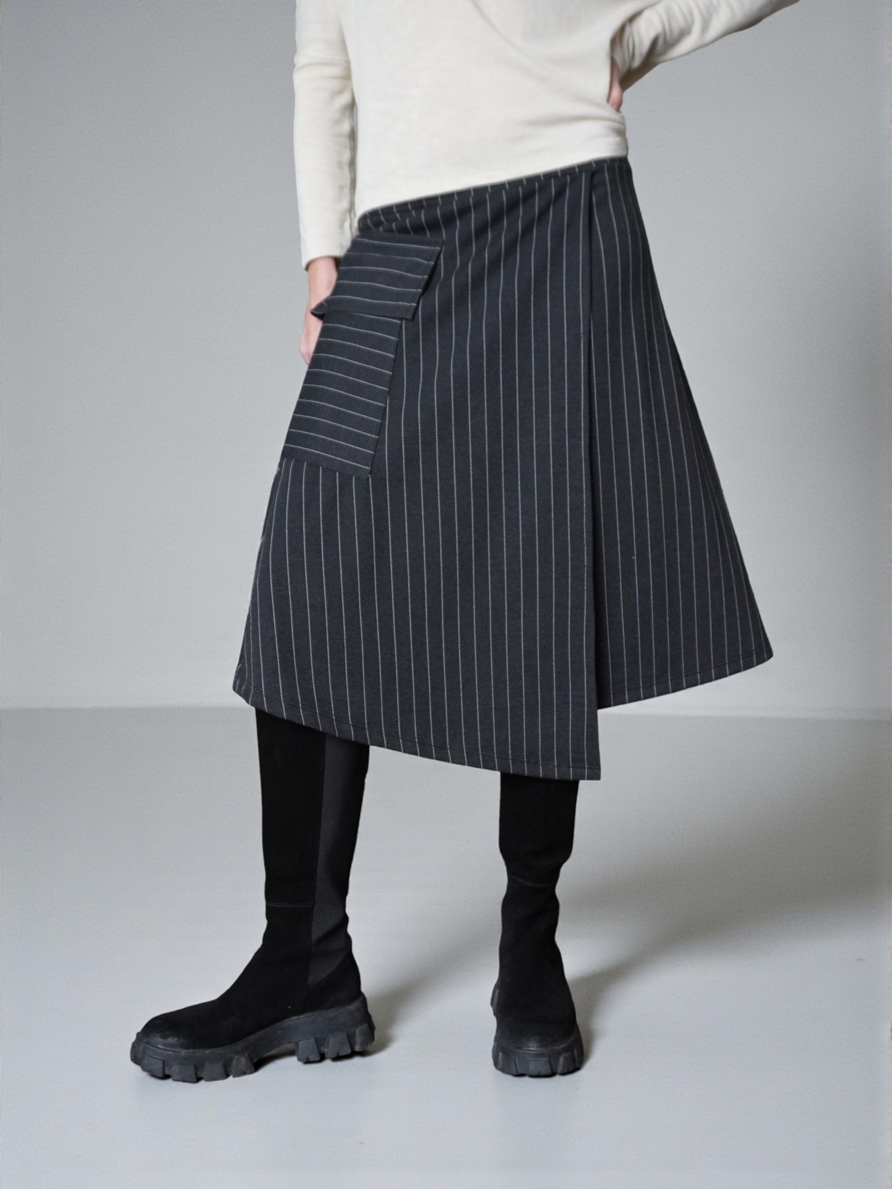 Fustă în dungi cu suprapunere frontală, surprinsă în mișcare, evidențiind fluiditatea materialului.