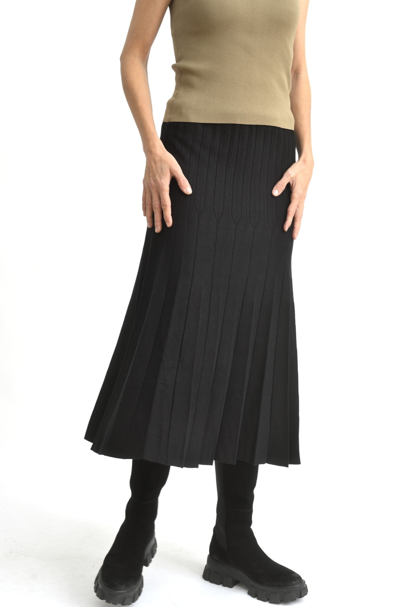 Fustă neagră din tricot ajurat, văzută din spate, cu talie elastică largă și pliseuri discrete.