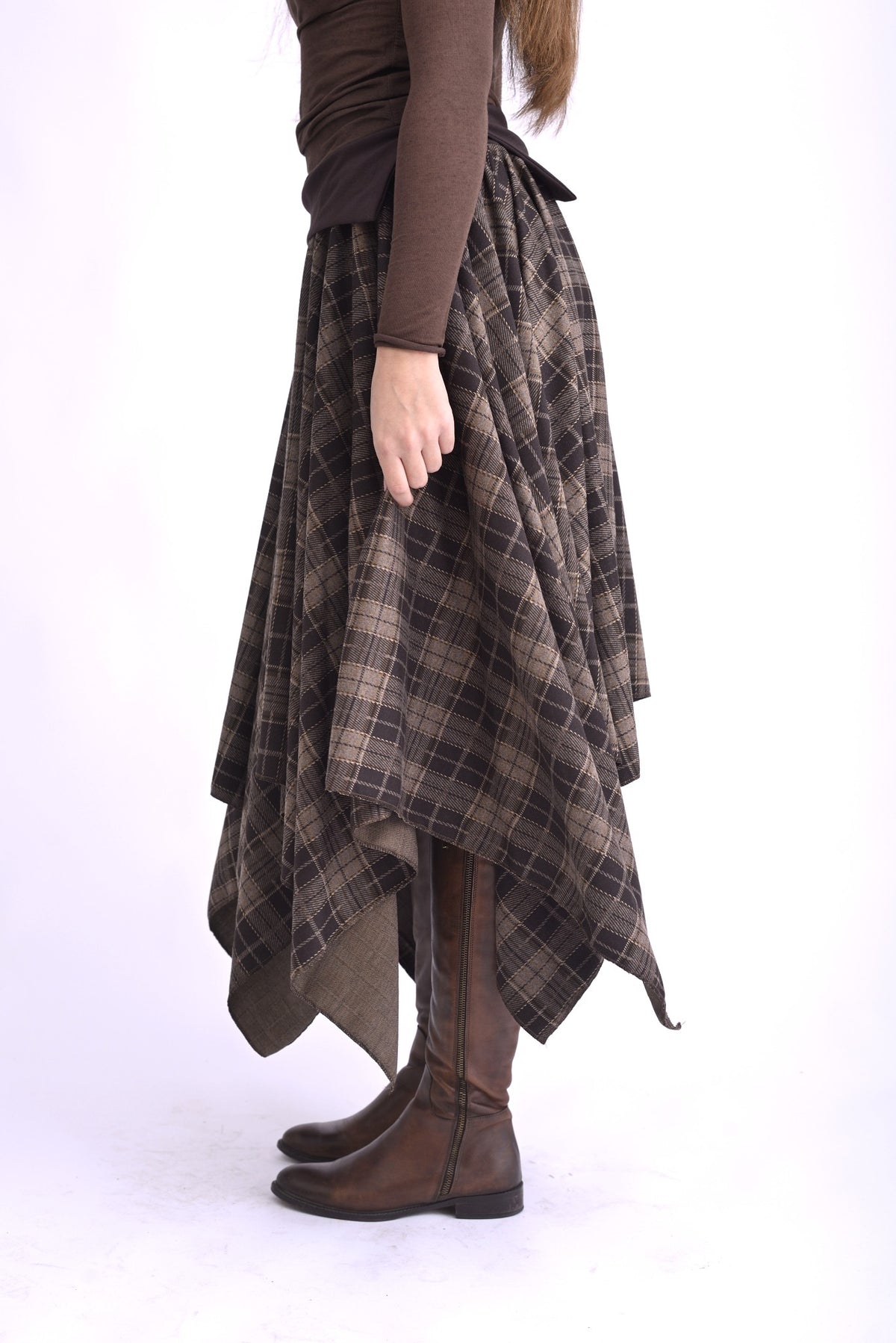 Detaliu de material al fustei în colțuri, țesătură texturată cu model în carouri, tonuri de maro, gri și negru.
