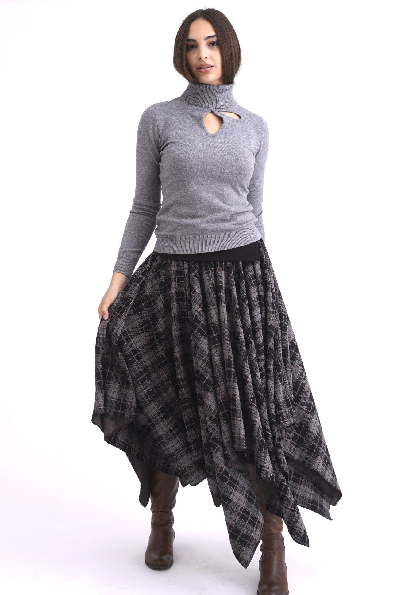 Fustă în colțuri, tiv asimetric cu falduri ample și croială modernă, purtată cu cizme maro.