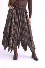 Fustă în colțuri, cu talie elastică și croială asimetrică, realizată din material în carouri, vedere din față pe model.