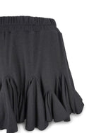 Detaliu al volanelor fustei scurte din jerse negru, cu textură elegantă și volum adăugat.
