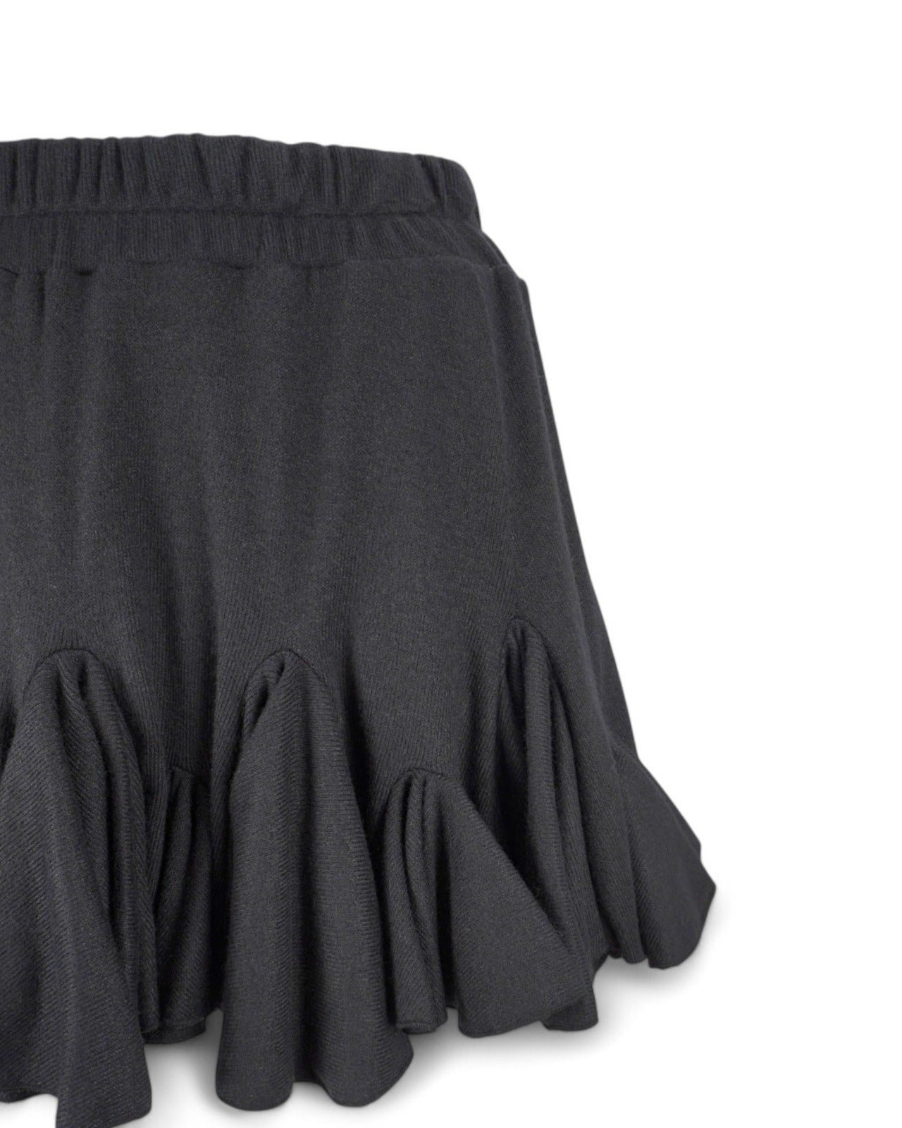 Detaliu al volanelor fustei scurte din jerse negru, cu textură elegantă și volum adăugat.