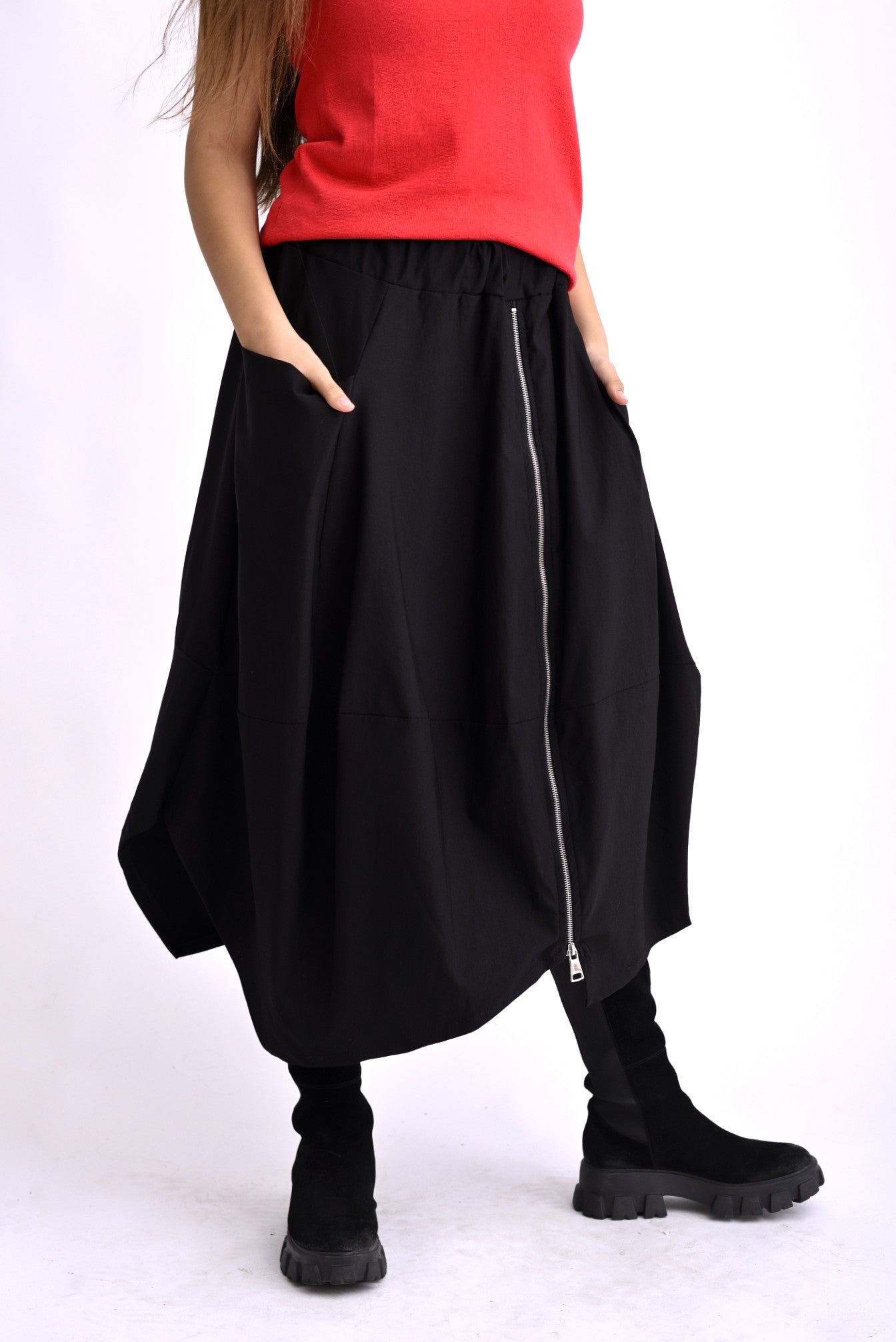 Fustă neagră cu material fluid, cădere amplă și detaliu de fermoar poziționat asimetric.