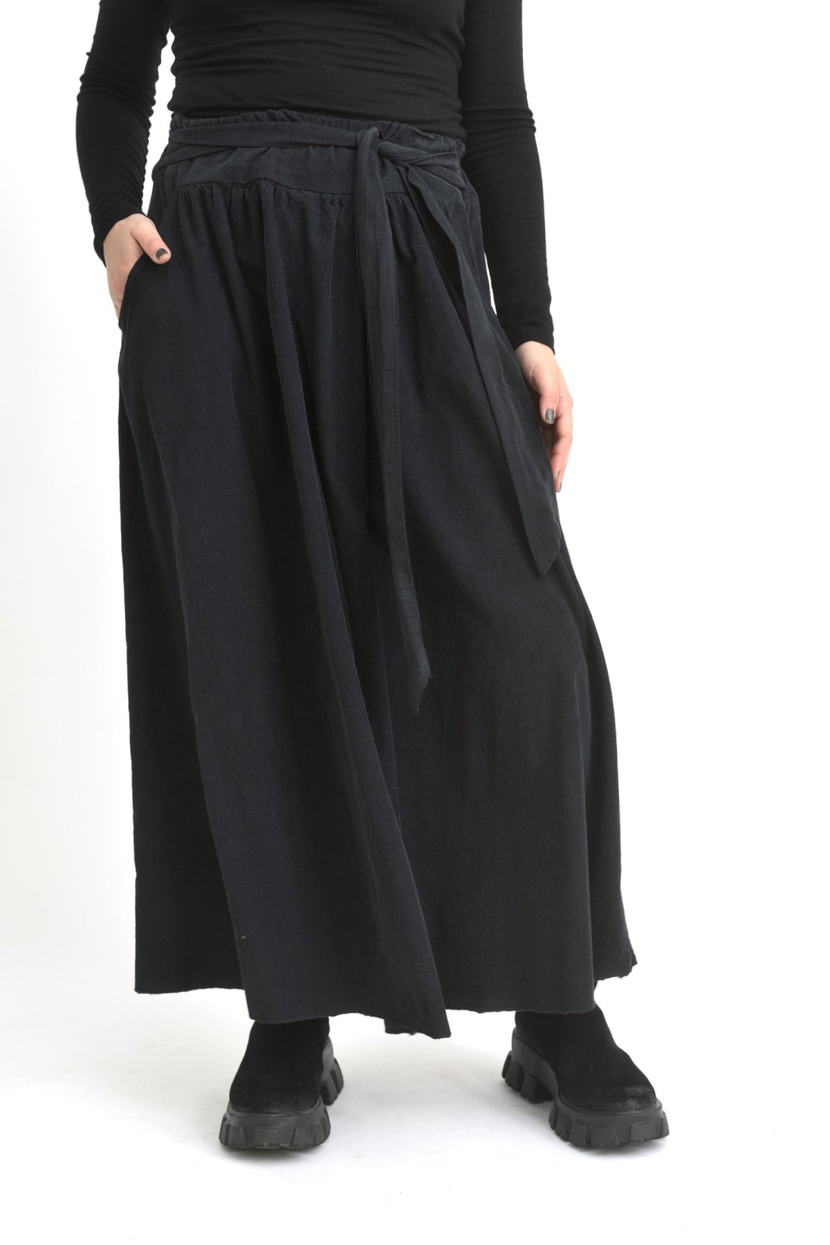 Fustă lungă neagră din catifea reiată, cu croială amplă și talie elastică, purtată pe model.