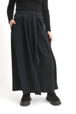 Fustă lungă neagră din catifea reiată, cu croială amplă și talie elastică, purtată pe model.