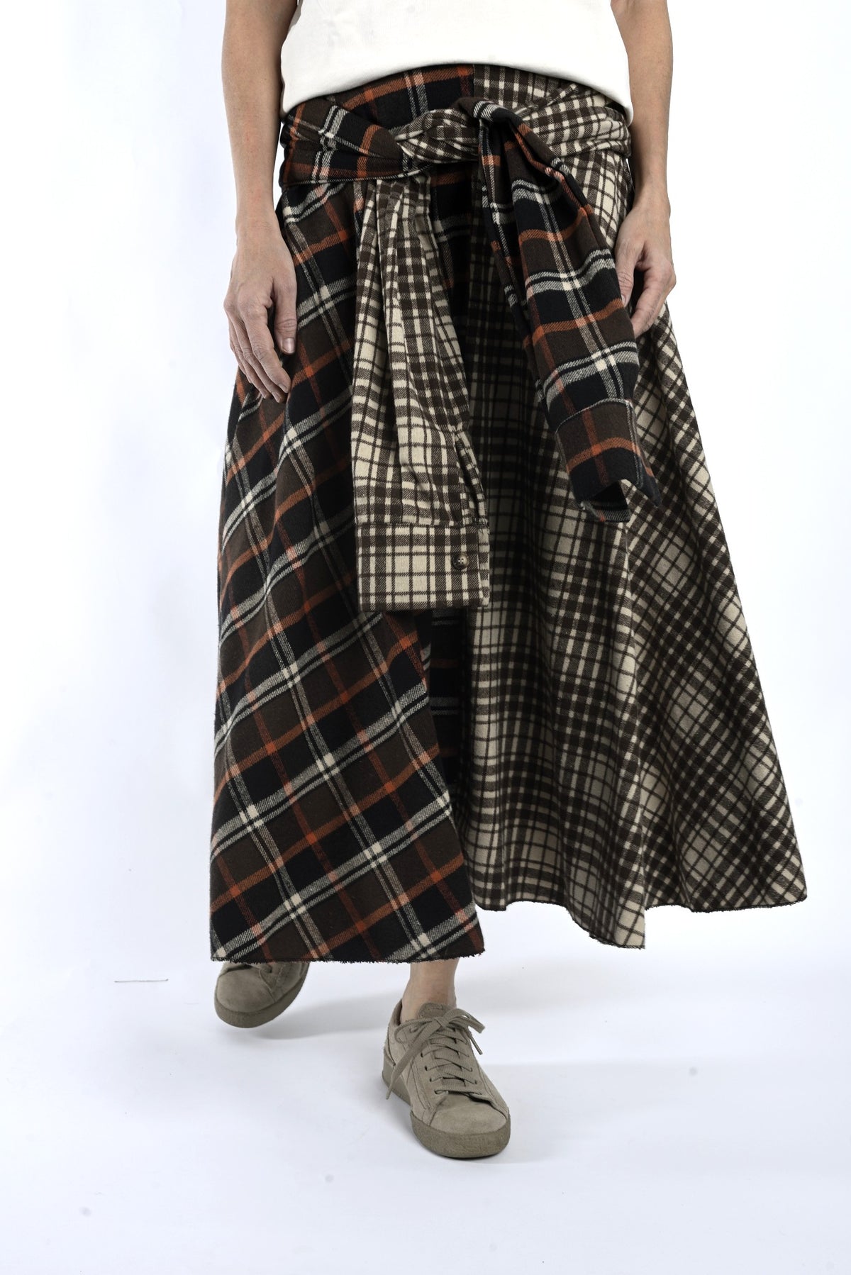 Detaliu de talie cu legare și suprapunere, evidențiind carourile contrastante ale fustei midi.